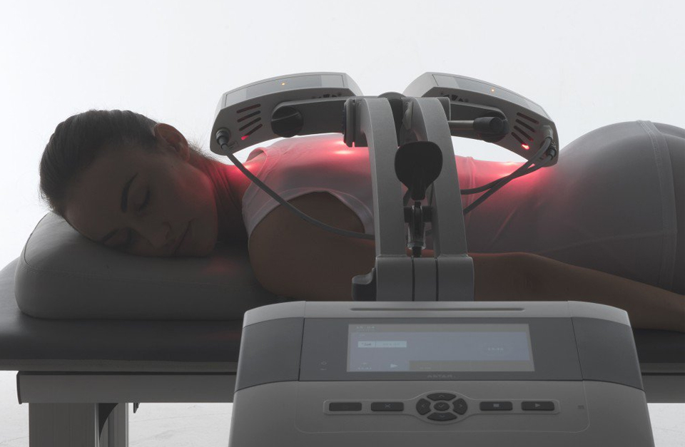 Frau liegt auf dem Bauch auf einer Therapieliege und unterzieht sich einer Behandlung mit dem CP-Plattenapplikator